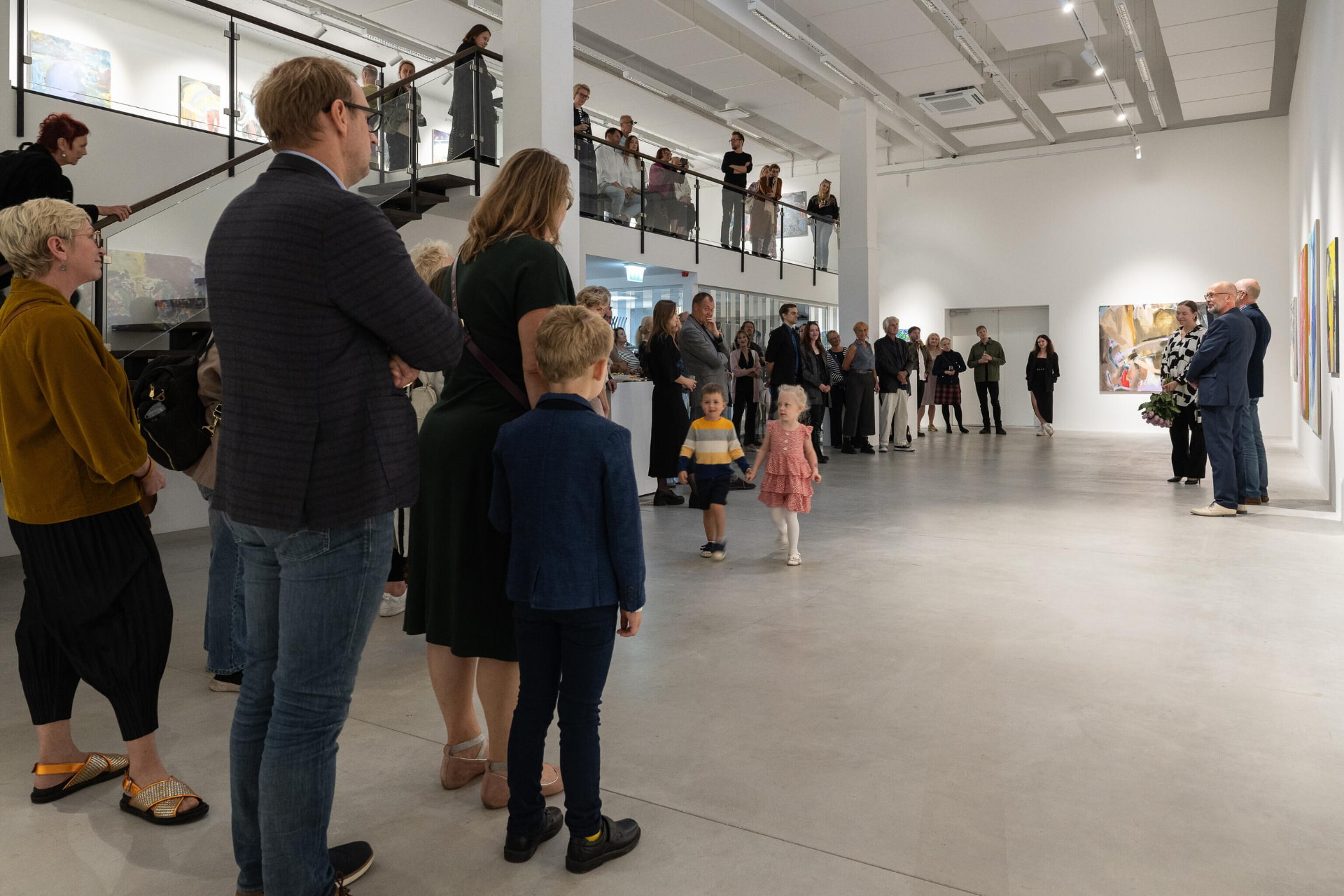 Guests at gallery exhibition opening with paintings