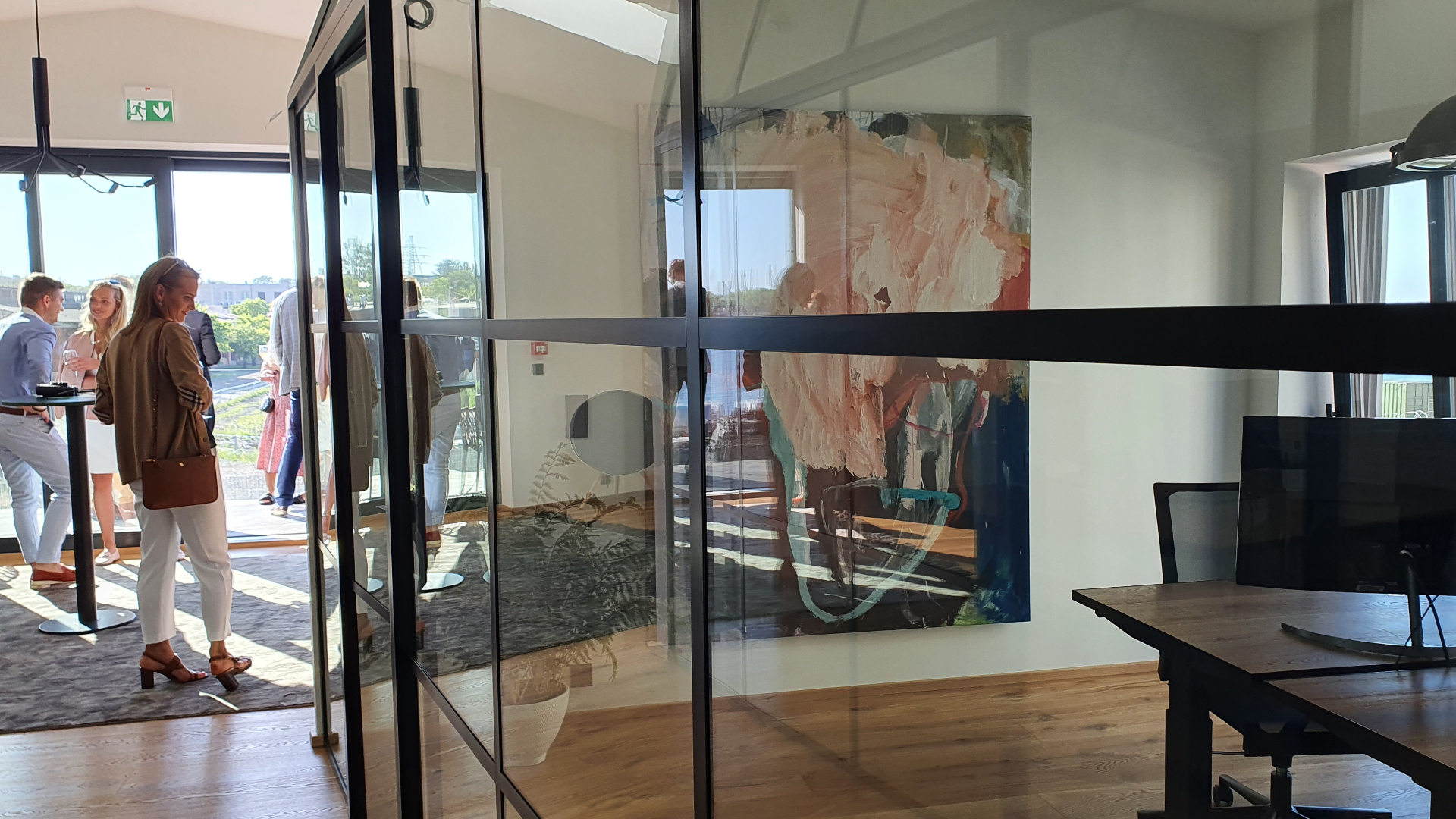 Large pink and teal abstract painting in modern office behind glass partition