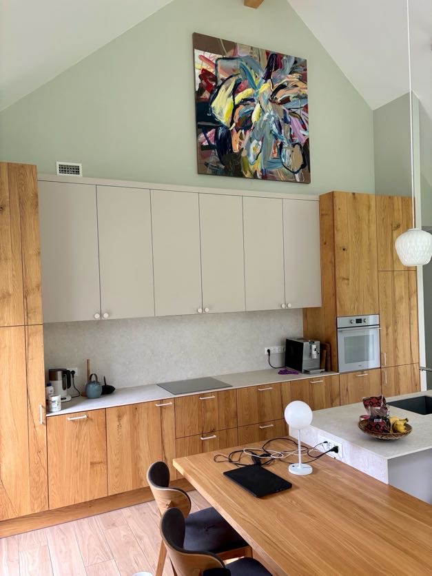 Colorful abstract painting above kitchen cabinets in bright vaulted interior